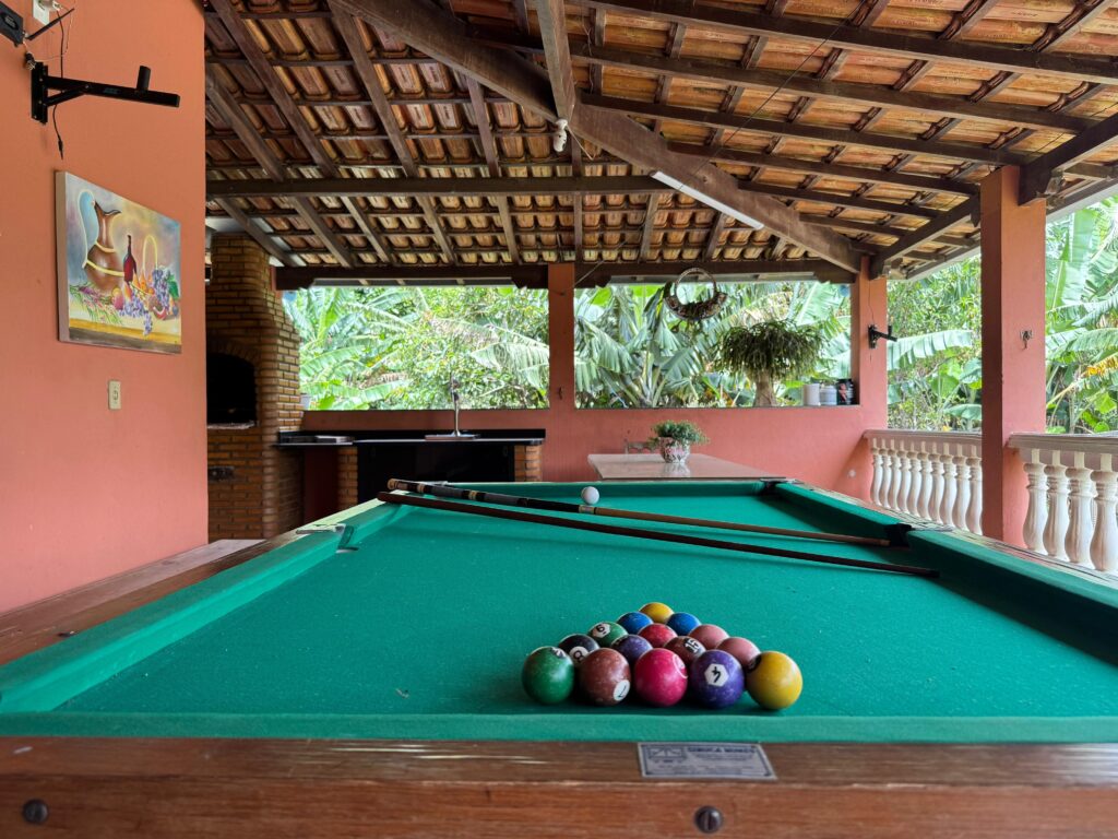 Mesa de sinuca profissional em área de jogos coberta no Recanto do Bem, Moeda, MG, com vista para a natureza.