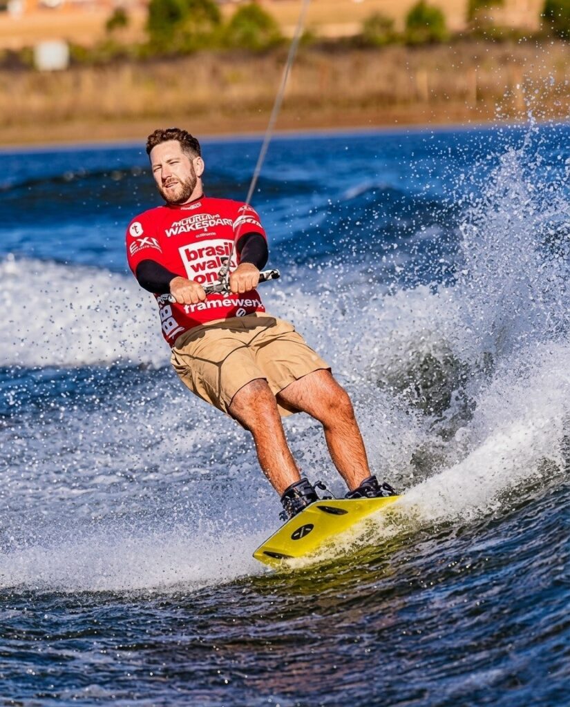 Atleta de wakeboard realizando manobra aérea com salto na Lagoa do Clube Serra da Moeda durante o Brasil Wake Open 2026.